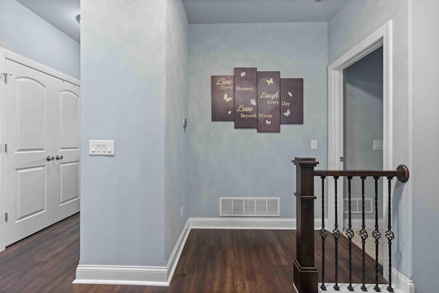 hallway featuring an upstairs landing, visible vents, baseboards, and wood finished floors