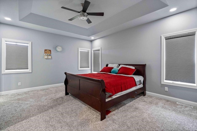 bedroom with a ceiling fan, baseboards, carpet floors, a tray ceiling, and recessed lighting