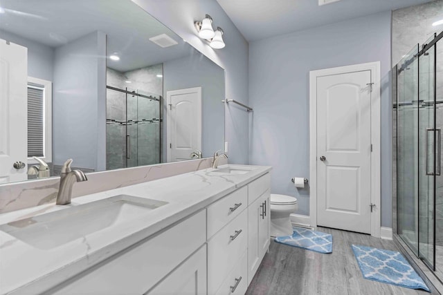 full bath with a shower stall, wood finished floors, double vanity, and a sink