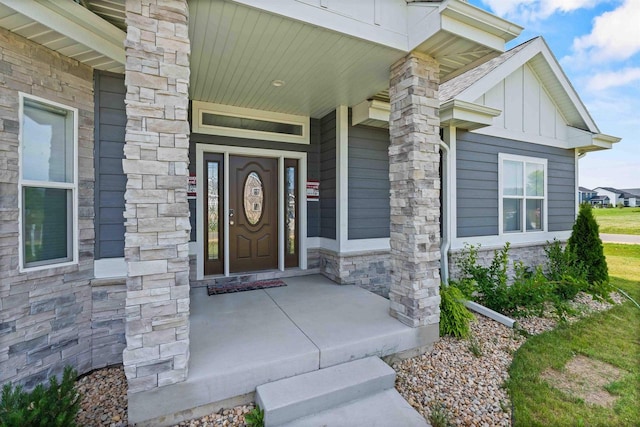 entrance to property with stone siding, covered porch, and board and batten siding