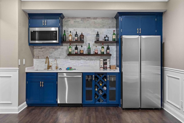 bar featuring a sink, wet bar, appliances with stainless steel finishes, and dark wood-style flooring