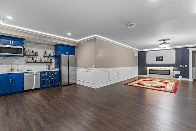 interior space featuring a fireplace, a sink, appliances with stainless steel finishes, crown molding, and blue cabinets