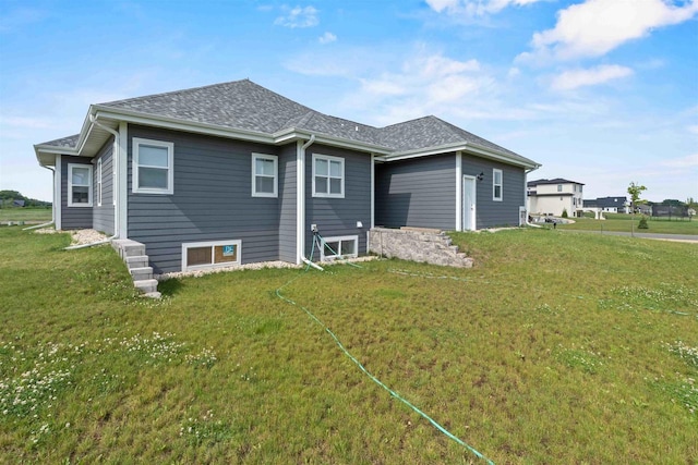 back of house with a lawn and roof with shingles