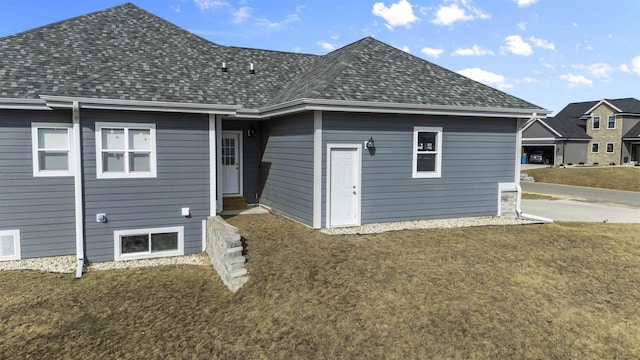 rear view of property with a shingled roof and a yard