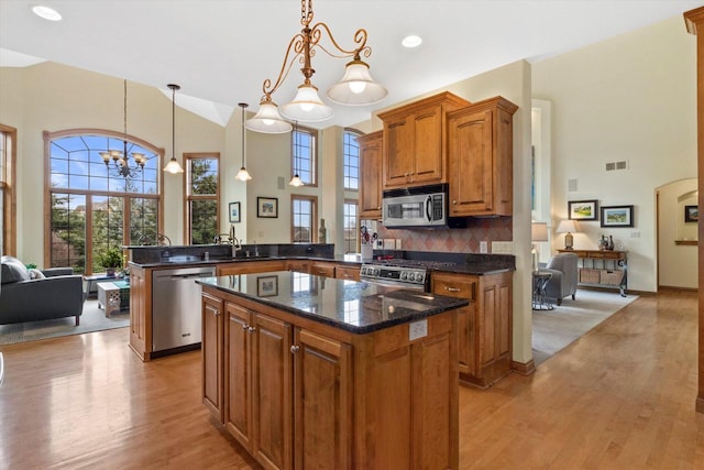 kitchen featuring visible vents, appliances with stainless steel finishes, a kitchen island, light wood-type flooring, and a peninsula