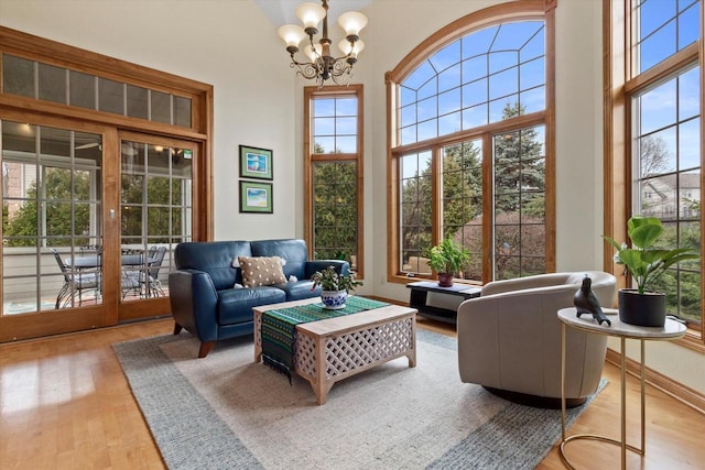 interior space with baseboards, wood finished floors, a towering ceiling, and a notable chandelier