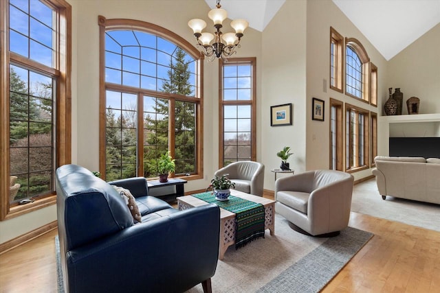 sitting room featuring light wood-style floors, baseboards, high vaulted ceiling, and a notable chandelier