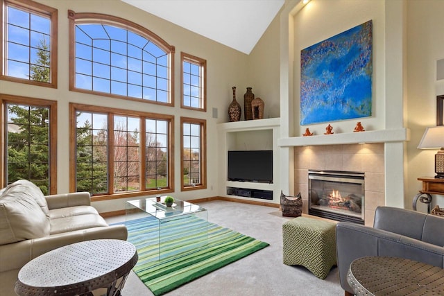 carpeted living room with high vaulted ceiling, built in shelves, a tiled fireplace, and baseboards