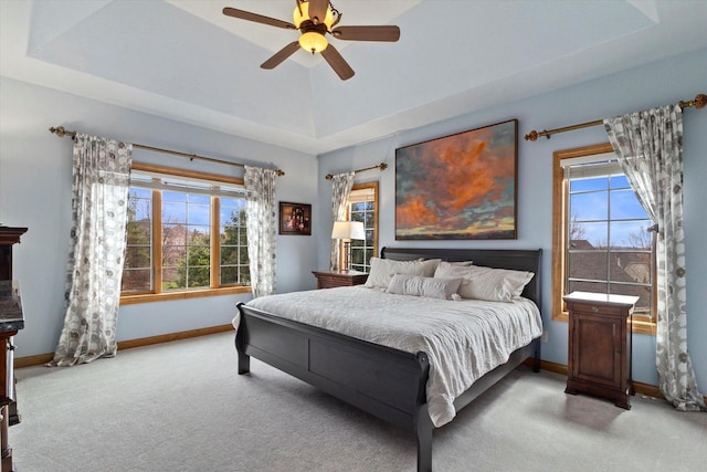 carpeted bedroom with a tray ceiling, ceiling fan, and baseboards