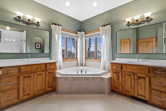 full bath with two vanities, tile patterned flooring, a sink, and a bath