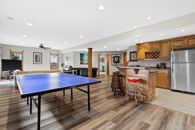 recreation room with decorative columns, recessed lighting, visible vents, light wood-style floors, and wet bar