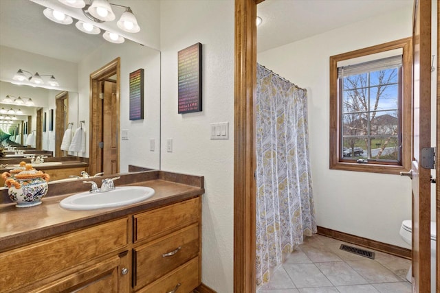 bathroom with tile patterned flooring, toilet, vanity, visible vents, and baseboards