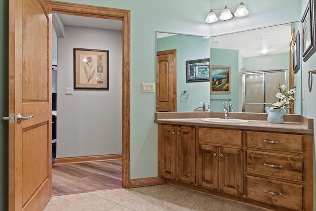 bathroom with a stall shower, tile patterned flooring, baseboards, and vanity