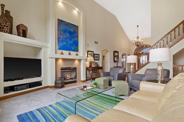 carpeted living room featuring arched walkways, a chandelier, a high ceiling, a fireplace, and stairs