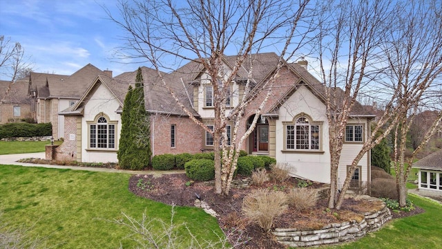 french country home with a front yard and brick siding