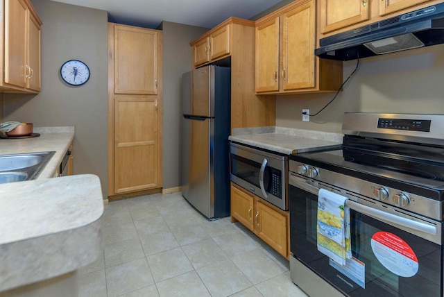 kitchen with appliances with stainless steel finishes, light countertops, under cabinet range hood, and light tile patterned floors