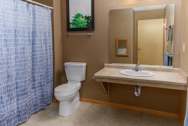 full bathroom featuring curtained shower, toilet, a sink, baseboards, and tile patterned floors