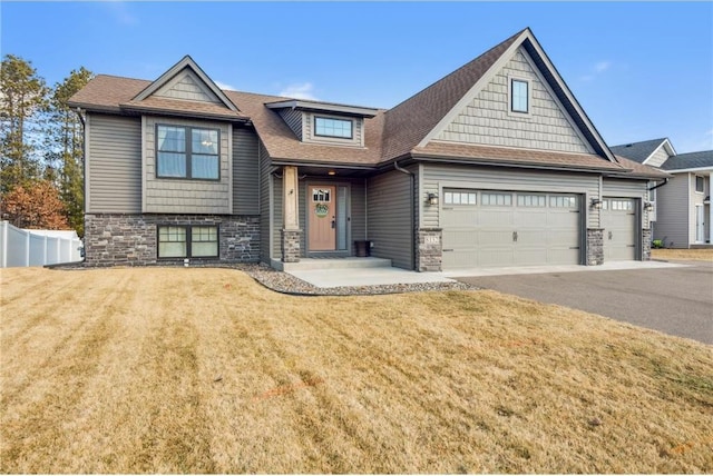 craftsman-style home with aphalt driveway, stone siding, fence, and a front lawn