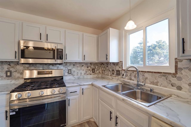 kitchen featuring tasteful backsplash, white cabinetry, stainless steel appliances, and a sink