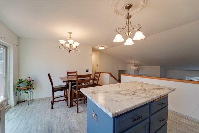 kitchen featuring light wood finished floors, light countertops, hanging light fixtures, an inviting chandelier, and blue cabinets