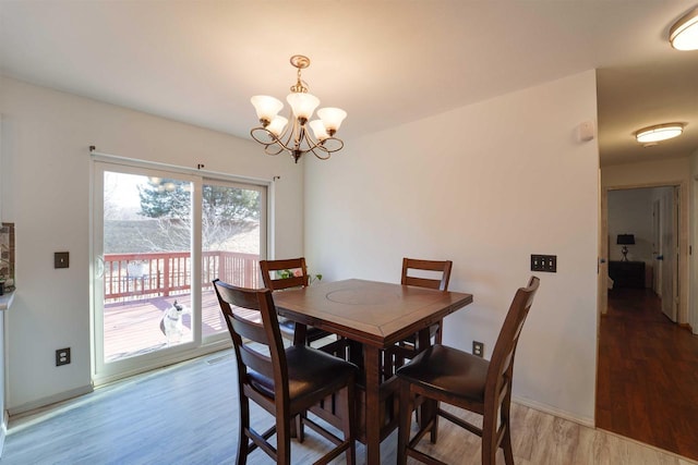 dining space featuring an inviting chandelier, baseboards, and wood finished floors