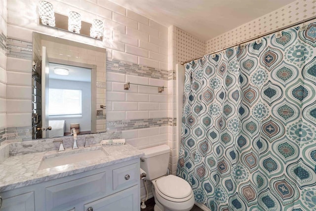 bathroom with toilet, a shower with curtain, tile walls, and vanity