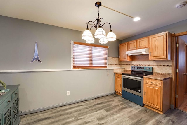 kitchen with tasteful backsplash, light wood-style floors, stainless steel electric range oven, under cabinet range hood, and pendant lighting