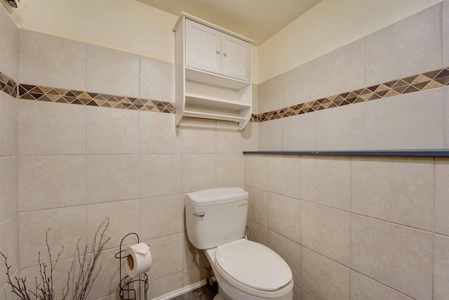 bathroom featuring tile walls and toilet