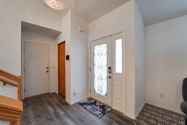 foyer entrance featuring vaulted ceiling, baseboards, dark wood finished floors, and a chandelier