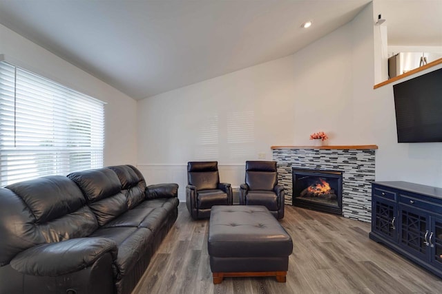 living room featuring wainscoting, a fireplace, vaulted ceiling, and wood finished floors