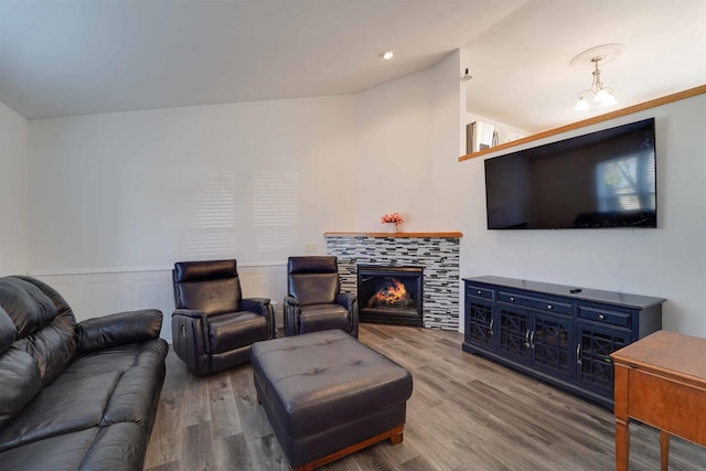 living area featuring lofted ceiling, a wainscoted wall, a fireplace, and wood finished floors