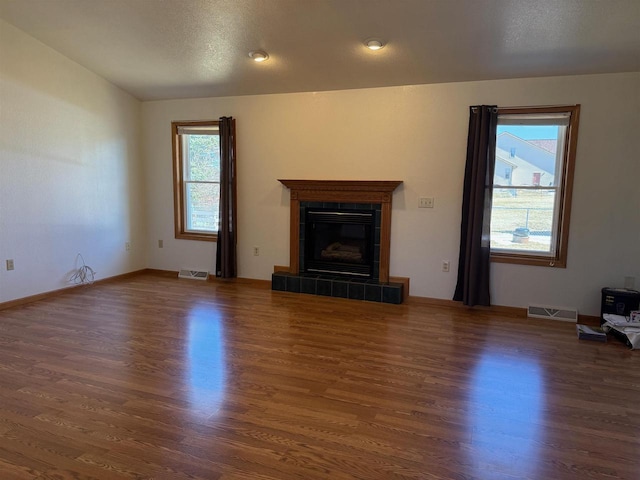 1080 Jaystone Ter, Waterloo, WI 53594 - unfurnished living room featuring a tile fireplace, visible vents, wood finished floors, and baseboards