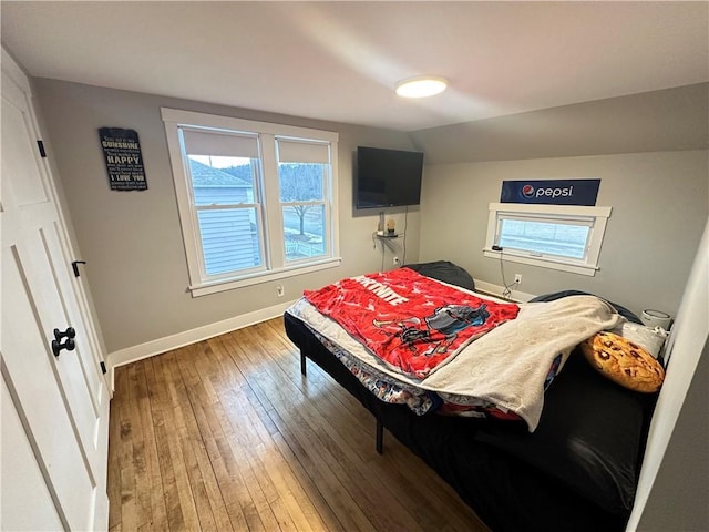 bedroom with lofted ceiling, multiple windows, baseboards, and hardwood / wood-style floors