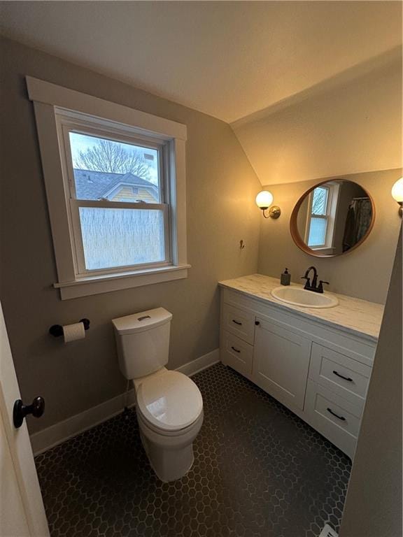 half bathroom featuring vaulted ceiling, vanity, toilet, and baseboards