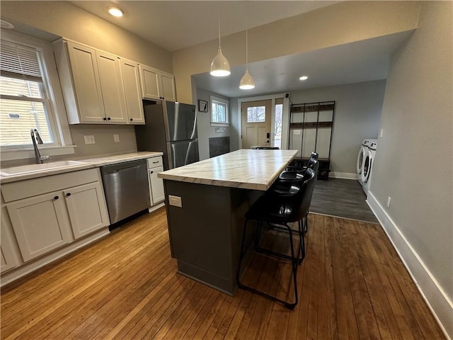 kitchen featuring light countertops, appliances with stainless steel finishes, a sink, and dark wood finished floors