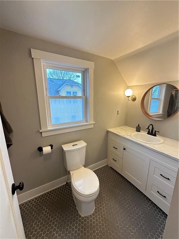 bathroom featuring toilet, baseboards, vaulted ceiling, and vanity