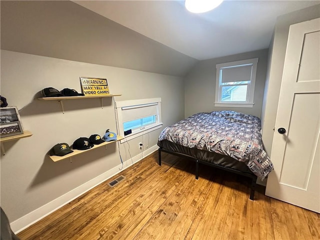 bedroom with wood-type flooring, visible vents, vaulted ceiling, and baseboards