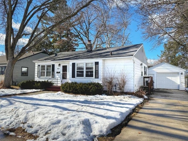 ranch-style home featuring an outbuilding, concrete driveway, a chimney, and a detached garage