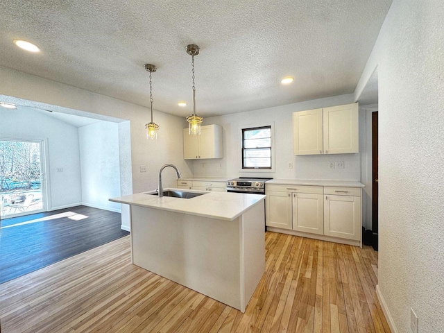 kitchen with light wood-style floors, stainless steel electric range oven, light countertops, and a sink