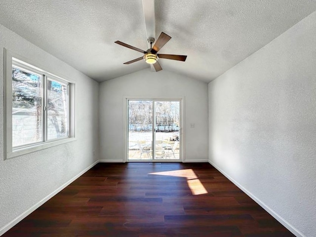 spare room featuring a textured ceiling, a textured wall, plenty of natural light, and wood finished floors