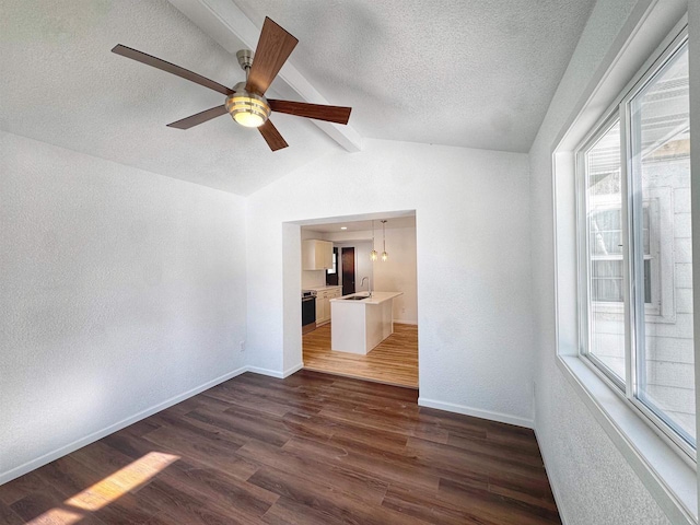 spare room with a textured ceiling, plenty of natural light, dark wood finished floors, and baseboards