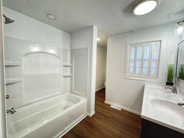 full bath featuring a textured wall, a sink, a textured ceiling, and wood finished floors