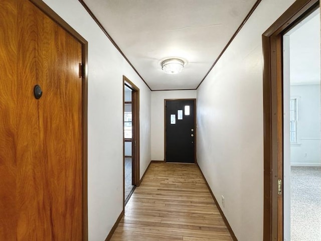 doorway to outside with light wood-style floors and ornamental molding