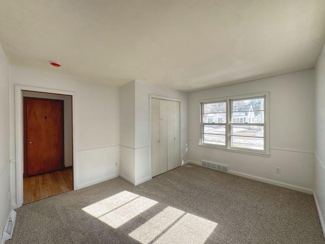 empty room with carpet flooring, visible vents, and baseboards