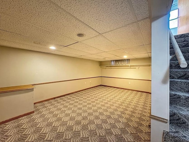 finished basement featuring carpet floors, stairway, a drop ceiling, and baseboards