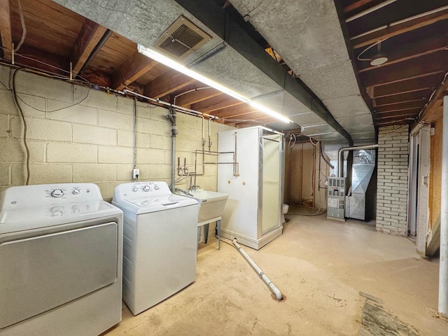 washroom featuring laundry area, visible vents, heating unit, separate washer and dryer, and a sink