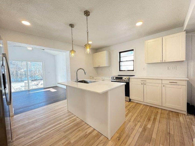 kitchen featuring stainless steel appliances, light countertops, white cabinetry, a sink, and light wood-type flooring