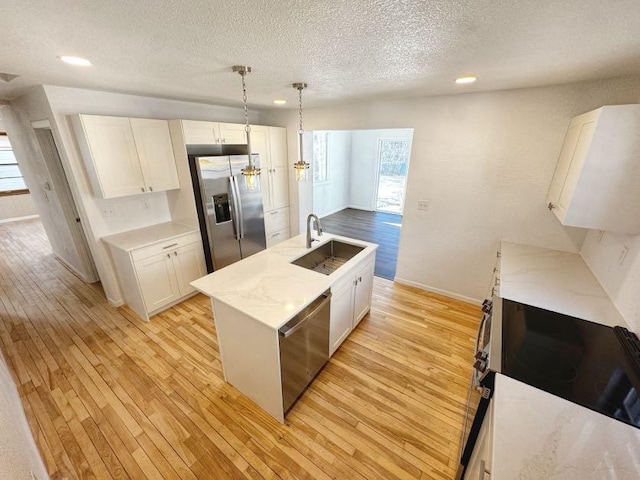 kitchen with light wood-style floors, white cabinetry, appliances with stainless steel finishes, and a sink