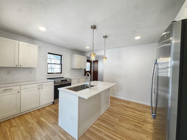 kitchen featuring light wood finished floors, white cabinets, appliances with stainless steel finishes, light countertops, and a sink