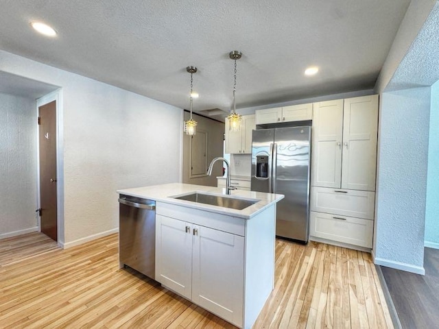 kitchen featuring stainless steel appliances, light wood-style floors, light countertops, and a sink